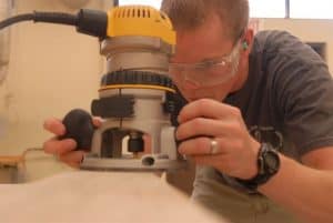 man uses a wood router in a wood working shop