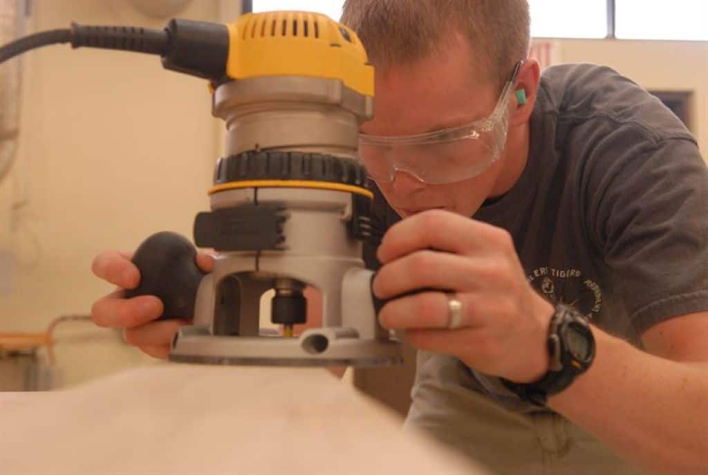 man uses a wood router in a wood working shop