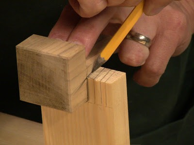 Person using pencil in marking piece of wood