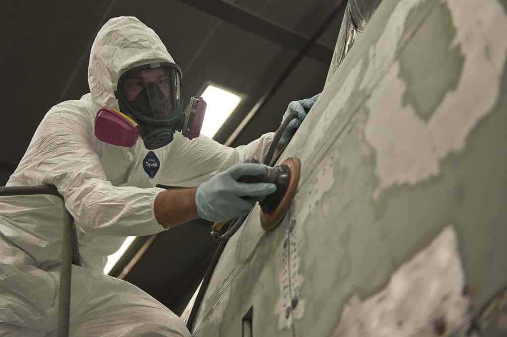 man uses a sander to remove paint