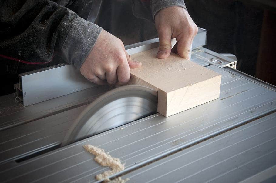 man working in a woodworking workshop uses a circular saw