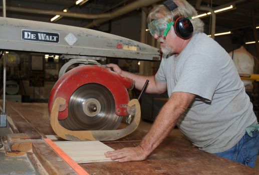 man operates a radial arm saw at a workshop